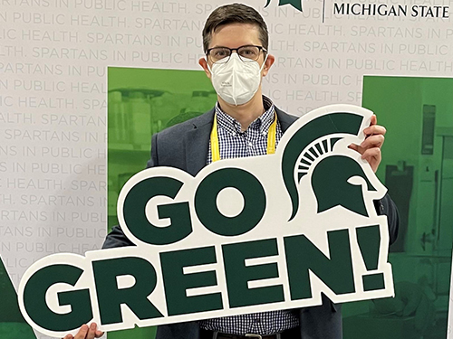 MPH Student Holding a "GO GREEN" sign
