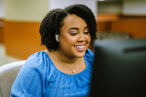 Person smiling sitting at a computer