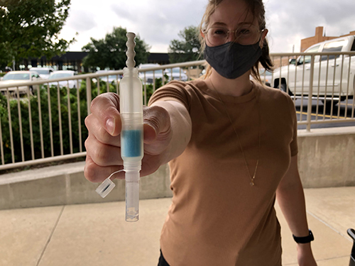 Student wearing a mask holding a test kit