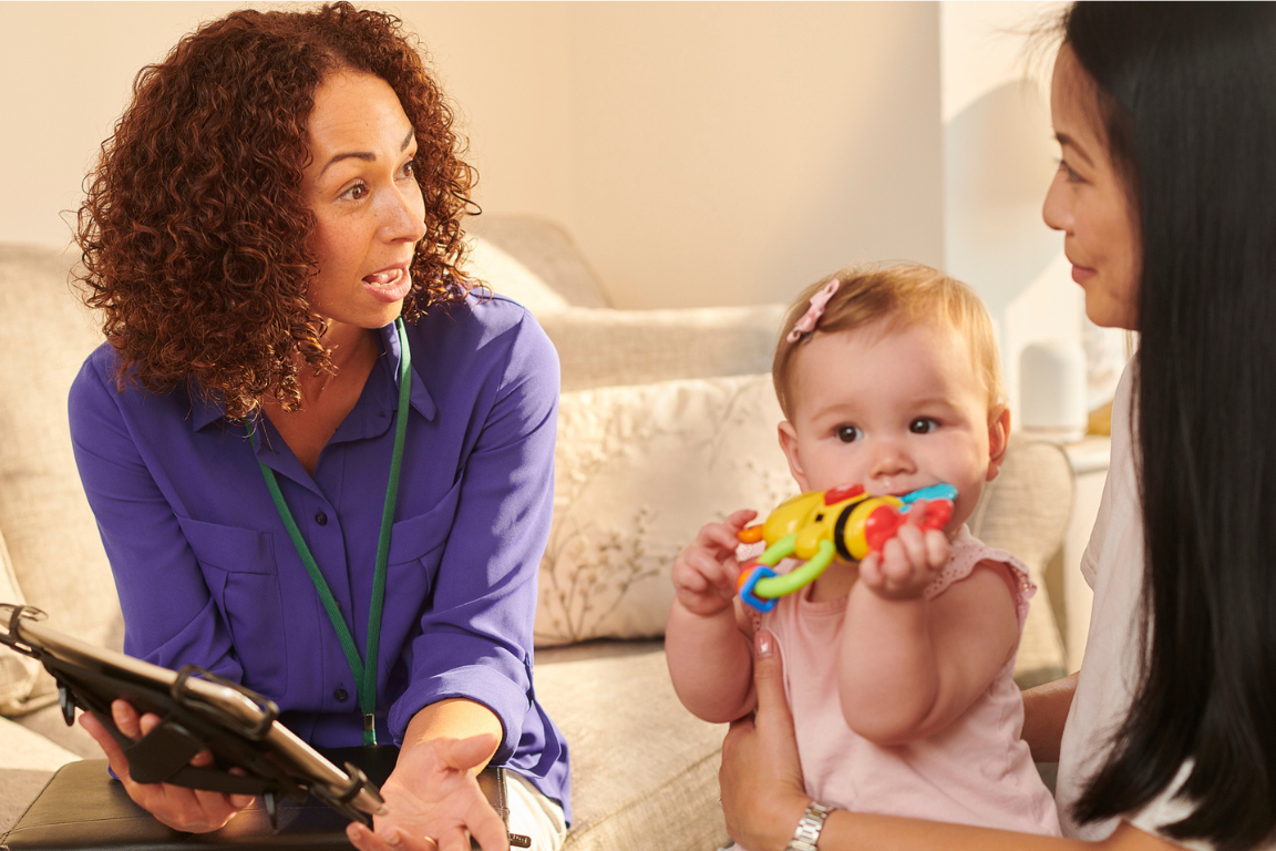 Social worker talking to mother holding baby